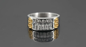 Macro shot of silver abacus ring with gold coin carvings on a reflective surface