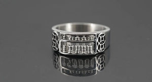 Macro view of vintage stainless steel abacus ring with rotatable beads and coin patterns