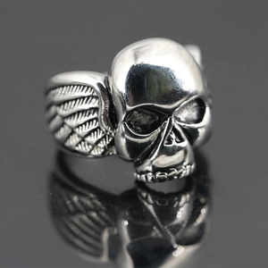 Retro-Punk-Totenkopfring mit Flügeln aus Vintage-Stahl auf einer schwarzen Reflexionsfläche
