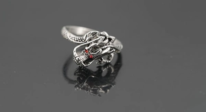 Detailweergave van een vintage zilveren drakenring met rode edelsteenogen en schubben