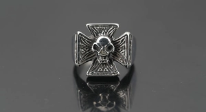 Macro shot of punk cross ring with skull detail and Norse rune engravings on silver metal
