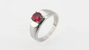 Primer plano de gema roja en banda ancha de metal cepillado con engaste clásico de cuatro garras