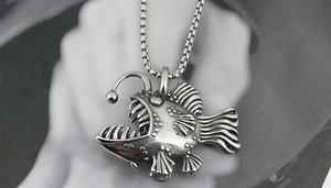 Macro shot of silver anglerfish pendant with realistic sharp teeth and box chain