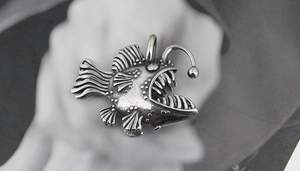 Macro view of vintage anglerfish pendant showing detailed scales and sharp teeth