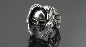 Detail of vintage skull ring featuring intricate feather carvings and blackened finish