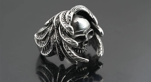 Macro view of vintage skull ring with detailed feather wings and brushed metal texture