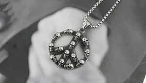 Detail view of retro stainless steel peace sign pendant with skull relief carvings