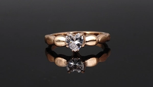 Close-up of a rose gold heart-shaped gemstone ring with a unique beaded band and 4-claw setting