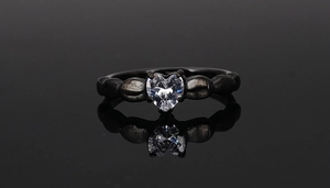 Macro view of black stainless steel ring featuring heart-shaped zircon and claw setting