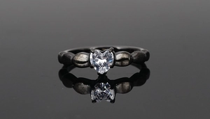 Detail of a heart-cut cubic zirconia set in a textured black titanium steel ring band