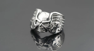 Macro detail of gothic skull ring with wings and cross engravings on polished metal