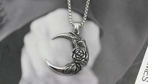 Macro shot of stainless steel crescent moon pendant with detailed rose and branch relief