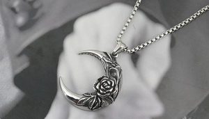 Detailed macro of crescent moon pendant with rose relief and stainless steel box chain
