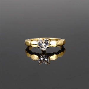 Golden heart-shaped crystal ring with beaded band design on reflective black background