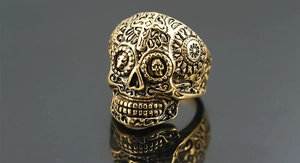 Makroaufnahme von Totenkopfring mit Vintage-Kreuzgravur und Sonnenmustern auf antikem Gold