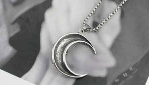 Macro shot of gothic crescent moon pendant in vintage silver with hollow details