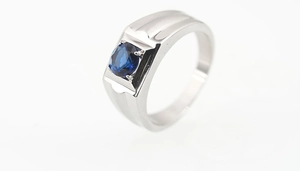 Close-up of stainless steel ring with a round blue sapphire in a four-prong setting