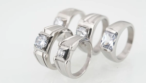 Macro shot of titanium steel couple rings with large white zircon stones and brushed finish