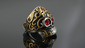 Détail d'une bague tête de mort vintage avec pierres rouges et reliefs dorés