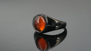 Macro shot of oval red agate gemstone set in a vintage black titanium steel ring band
