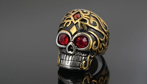 Détail d'une bague tête de mort gothique avec gemmes rouges et finition bicolore argent