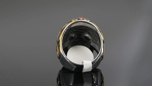 Détail macro d'une bague tête de mort vintage avec relief doré et pierre rouge incrustée