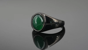 Macro shot of polished gunmetal signet ring featuring a smooth round green agate gemstone