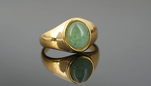 Close-up of a gold titanium ring featuring an oval green tiger eye stone with reflections