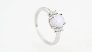 Detalle de anillo de plata con una opala redonda central y circones laterales