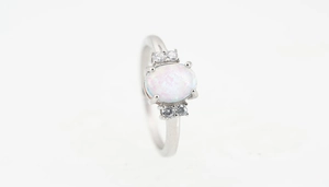 Detalle del anillo de acero de titanio con ópalo de fuego blanco y piedras de circón