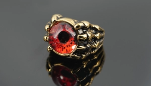 Gros plan détaillé d'une bague griffe de dragon avec œil du démon rouge et finition dorée
