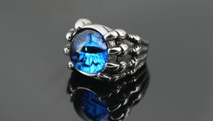 Détail macro d'une bague griffe de dragon gothique tenant un œil bleu vif
