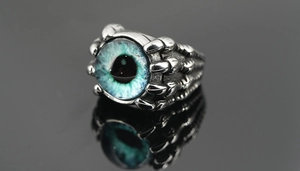 Vue macro d'une bague gothique punk en acier avec griffe d'aigle et œil bleu serti