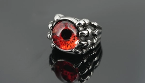 Vue macro d'une bague gothique en acier titane avec un œil du diable rouge et serti griffes
