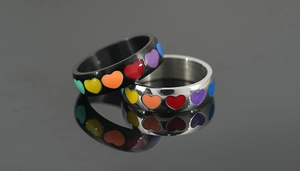 Detailed macro view of black and silver stainless steel rings with rainbow heart patterns