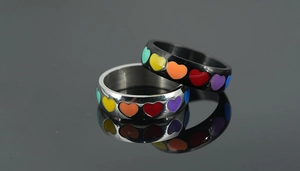 Macro shot of silver and black titanium rings with colorful enamel rainbow heart patterns