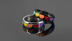 Macro detail of silver and black stainless steel rings with rainbow enamel hearts