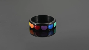 Macro shot of black titanium ring featuring colorful rainbow heart oil drip patterns