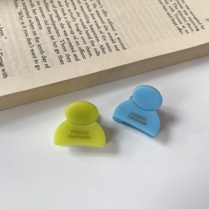 Dettaglio di piccole pinze per capelli in acetato giallo e blu con scritta France Handmade
