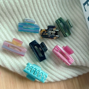 Set of 7 colorful acetate mini hair clips with gold label on soft knit background