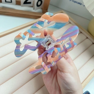 Detailed view of a large rainbow acrylic butterfly hair claw clip with a glossy finish