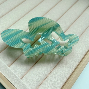 Detail of butterfly hair claw clip with green marbled acetate finish on cream tray
