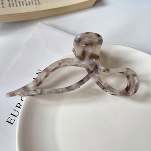 Détail d'une pince à cheveux élégante en acétate avec motif marbre sur assiette