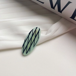 Détail de la barrette ovale en acétate vert clair avec lettrage doré France Handmade