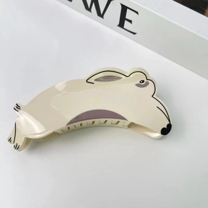 Détail d'une pince à cheveux en acétate en forme de chien crème avec accents gris sur blanc