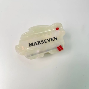Détail d'une pince à cheveux lapin en acétate blanc avec lettrage Marseven élégant