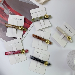 Detailed view of acetate hair clip featuring marble patterns and a golden embossed round buckle