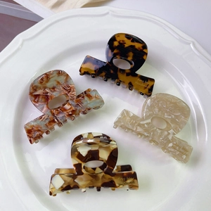 Detailed set of four handmade marble patterned acetic acid small hair claws on white plate