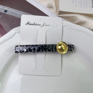 Close-up of tortoise shell hair clip with gold metal buckle on white display card