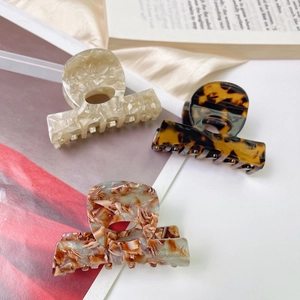 Three acetate hair claws with marble and tortoiseshell patterns in a cozy setting